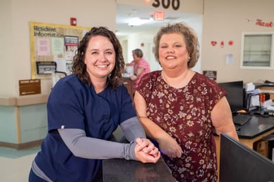 Two staff members smiling in the facility lobby