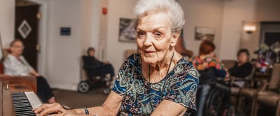 Resident playing piano in a lively common area