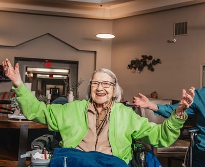 Resident smiling with arms raised in a common area