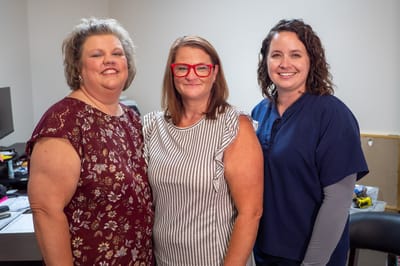 Three staff members posing in a bright room
