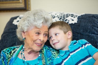 An elderly woman smiling with a young boy in a cozy setting