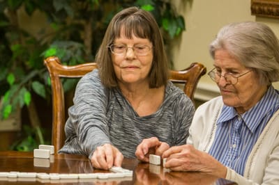 Two residents playing dominoes at a table