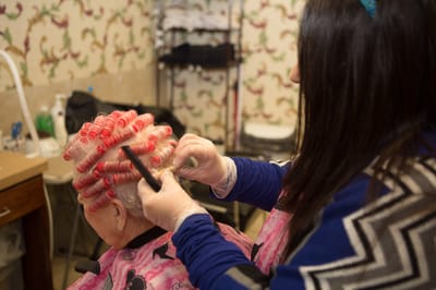 Resident receiving a hair treatment in a common area