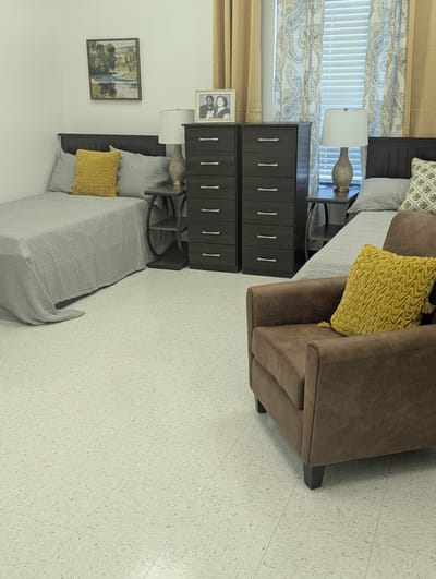 A cozy private resident room with twin beds and furniture