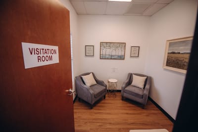 A cozy visitation room with two chairs and artwork