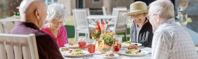 Residents enjoying a meal at an outdoor dining setting
