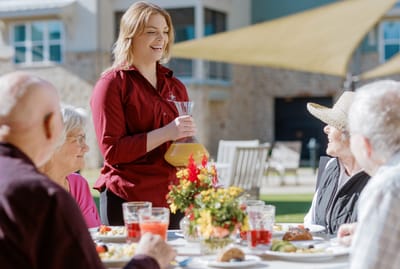 Staff serving beverages to residents at an outdoor dining area