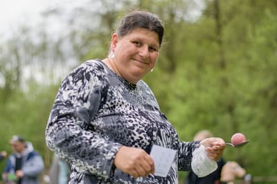 Person holding a spoon and a dessert outdoors