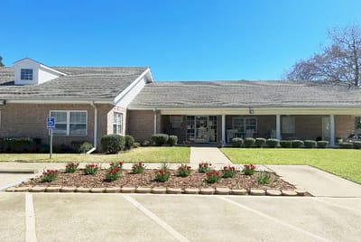 Front exterior of Pine Lodge Assisted Living with flowers