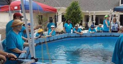 Seniors participating in a fishing activity by a pool