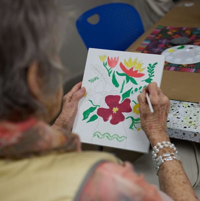 Resident painting a floral design in an activity