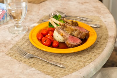 A plate of lamb chops with vegetables served at a dining table
