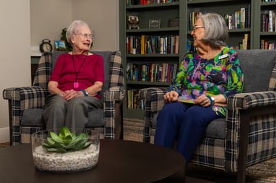Two residents chatting in a cozy common area