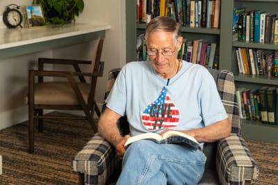 Resident reading a book in a cozy chair