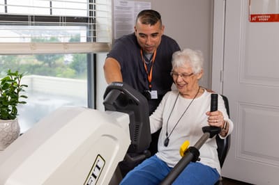 Resident engaging with a staff member on exercise equipment