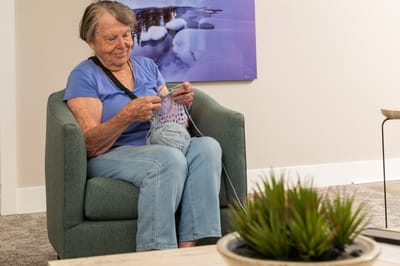 Resident knitting in a cozy lounge area