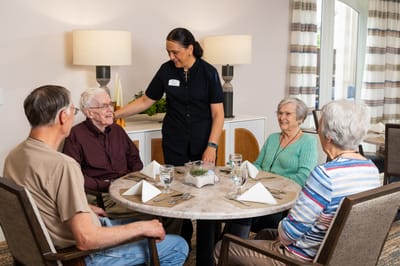 Residents enjoying a meal with staff in the dining area