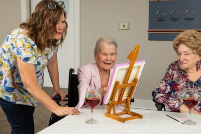 Residents enjoying a painting activity with staff assistance