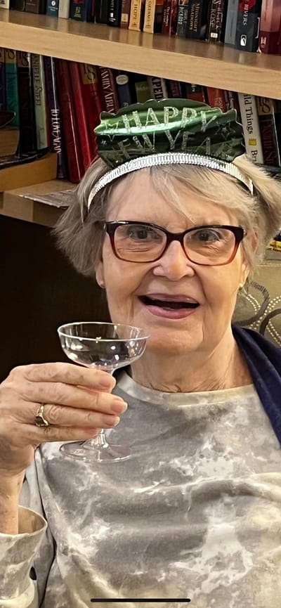 A joyful resident celebrating with a drink and a festive hat