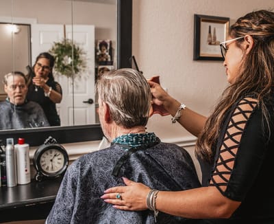 Stylist providing a haircut to a male resident