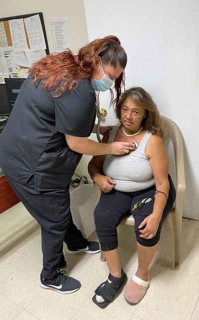Nurse checking a resident's vitals in an interior space