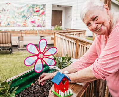 A resident gardening with a decorative flower and birdhouse