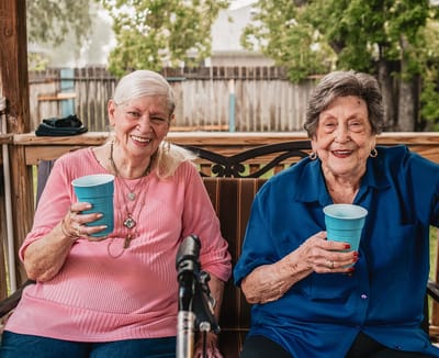 Two residents smiling and enjoying drinks outdoors