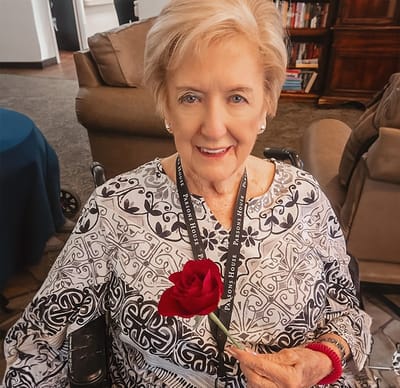 A resident smiling with a rose in a common area