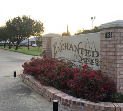 Sign for Enchanted Pines with flowerbed