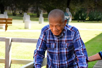 Elderly man outdoors, smiling in a garden setting