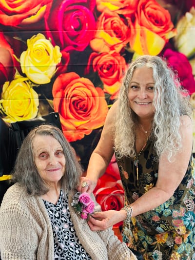 Staff member assisting a resident with a corsage