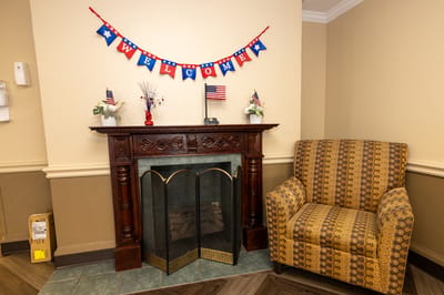 Crestwood Assisted Living, Nursing Home in Harrisonburg, VA — Decorative fireplace with a welcoming banner and armchair