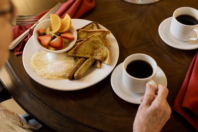 A breakfast plate with eggs, sausage, toast, and fruit.