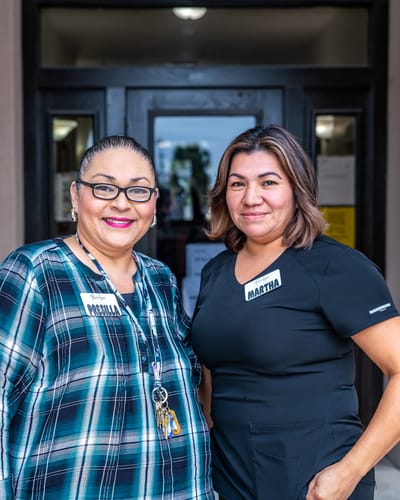 Staff members smiling outside the facility entrance