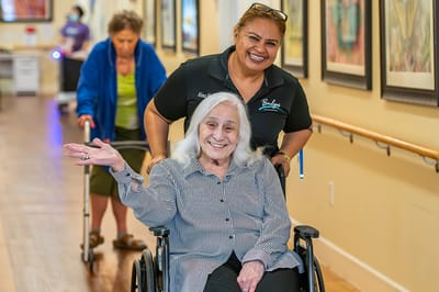 Staff assisting residents in a bright corridor