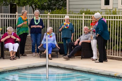 Residents enjoying a poolside gathering with leis and drinks