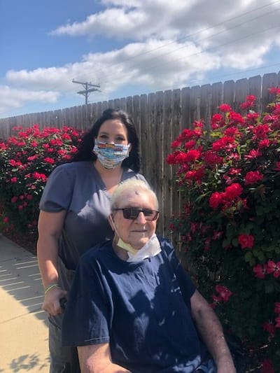 Staff member assisting a resident outdoors near flowers