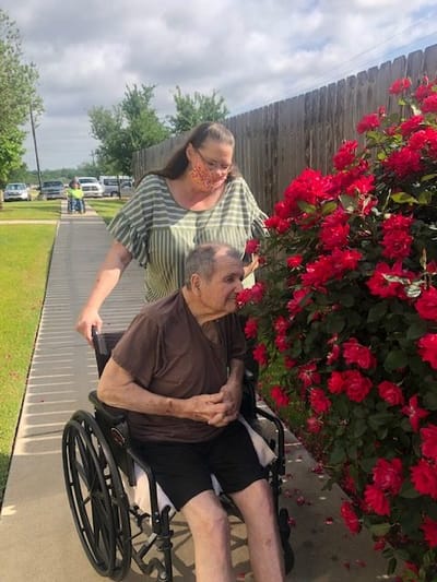 Resident enjoying roses with a caregiver outside
