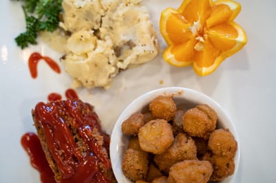 A plate of food featuring meatloaf, mashed potatoes, and orange slice
