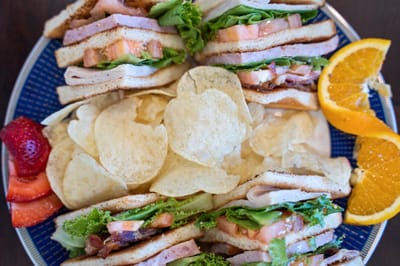 A platter of sandwiches with chips and fruit