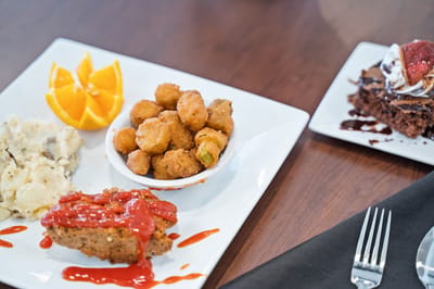 A meal with meatloaf, mashed potatoes, and dessert.