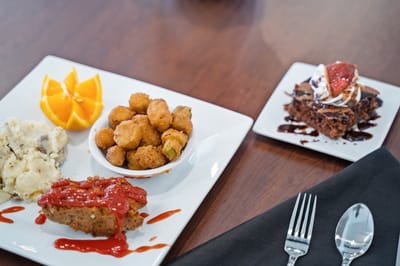 A beautifully served meal featuring chicken, sides, and dessert