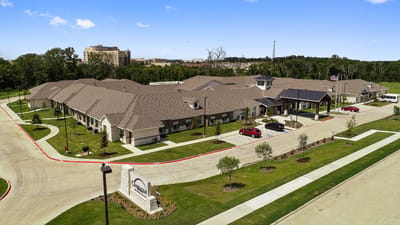 Aerial view of the senior living facility with gardens and parking