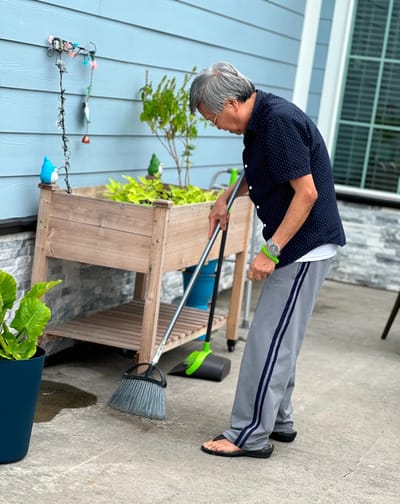 Elderly man tending to plants in a garden area