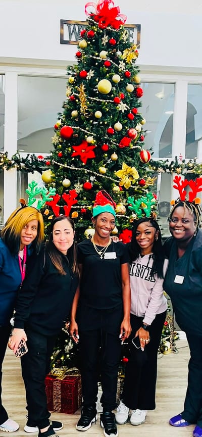 Staff members celebrating in front of a decorated Christmas tree