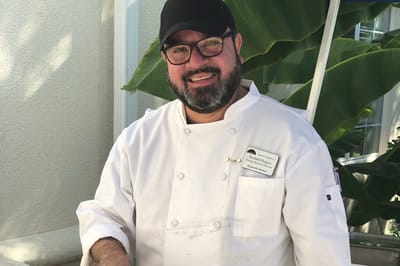 Chef smiling outdoors in a culinary setting