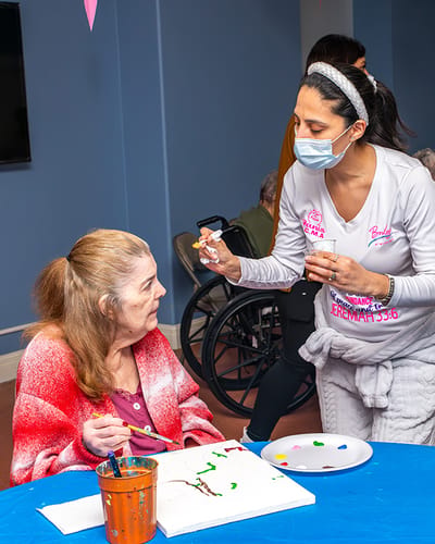 A resident and a staff member painting together