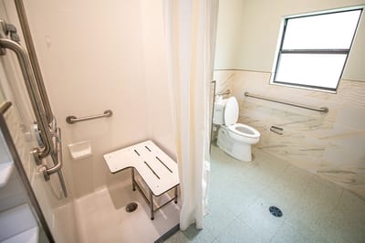 Accessible bathroom with grab bars and shower bench.