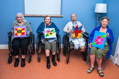Residents showcasing their artwork in an activity room