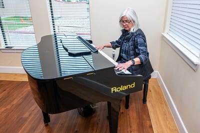 Resident playing piano in a sunny activity room